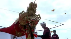 Pria Bali bersiap menaikan layang-layang saat mengikuti lomba layang-layang tradisional dalam festival layang-layang di Bali, Indonesia, (6/8). Festival ini diselenggarakan untuk mempromosikan pariwisata di pulau resor. (AP Photo/Firdia Lisnawati)