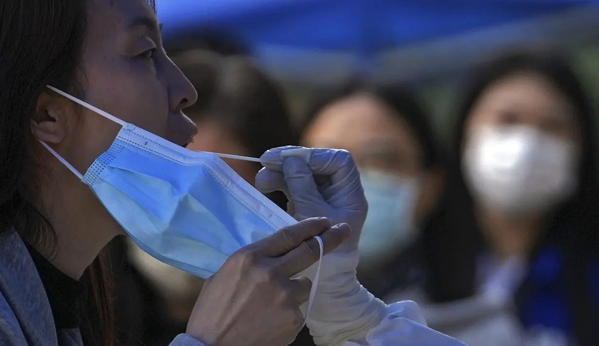 <p>Seorang perempuan memegang maskernya saat tes usap selama pengujian COVID-19 publik di distrik Chaoyang, Beijing, Rabu (11/5/2022). Shanghai pada Rabu menegaskan kembali akan mempertahankan pendekatan &ldquo;nol-COVID&rdquo; pengendalian pandemi, sehari setelah kepala Organisasi Kesehatan Dunia (WHO) menyatakan kebijakan itu tidak berkelanjutan dan mendesak China mengubah strategi. (AP Photo/Andy Wong)</p>