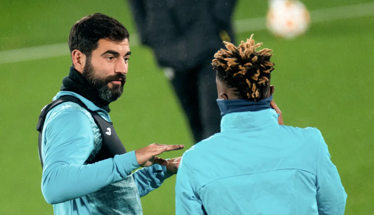 Bek Villarreal Raul Albiol berbicara dengan gelandang Villarreal Samuel Samuel Chukwueze selama sesi latihan di Ciudad Deportiva Villarreal di Vila-Real, Senin (22/11/2021). Villarreal bakal menjamu Manchester United dalam lanjutan Liga Champions, Selasa (23/11) waktu setempat. (JOSE JORDAN / AFP)