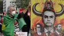 Seorang demonstran berfoto di samping spanduk yang menggambarkan Jair Bolsonaro selama protes menuntut presiden Brasil itu mengundurkan diri, di Sao Paulo, Sabtu (3/7/2021). Puluhan ribu orang turun ke jalan menuntut pemakzulan Presiden Jair Bolsonaro. (AP Photo/Nelson Antoine)