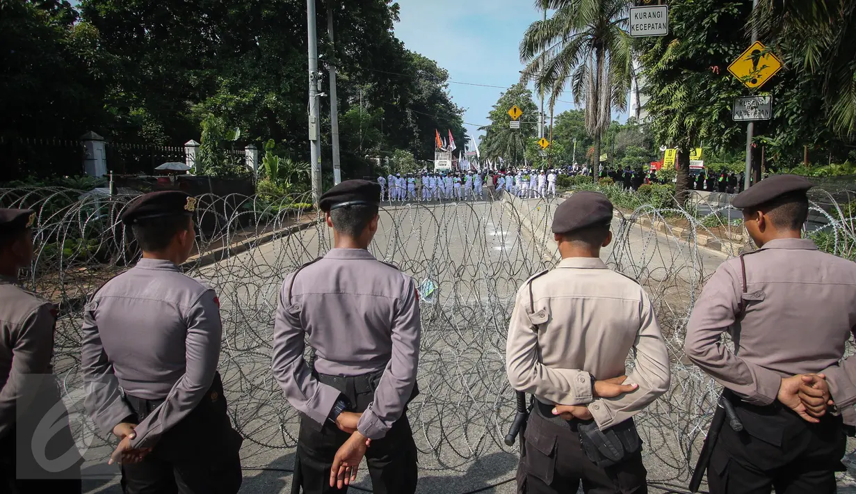 Aparat kepolsian berjaga di balik kawat berduri yang terpasang di luar Kementerian Pertanian, Jakarta, Selasa (9/5). Pihak kepolisian mengawal sidang pembacaan putusan terhadap Basuki Tjahaja Purnama alias Ahok. (Liputan6.com/Faizal Fanani)