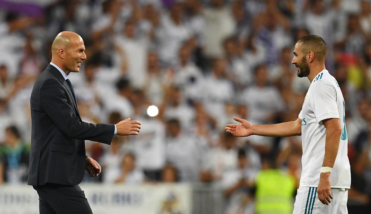 Pelatih Real Madrid, Zinedine Zidane, bersalaman dengan Karim Benzema usai mengalahkan Barcelona di Stadion Santiago Barnabeu, Rabu, (16/8/2017). Karim Benzema resmi memperpanjang masa bakti bersama Los Blancos hingga Juni 2021. (AFP/Gabriel Bouys)