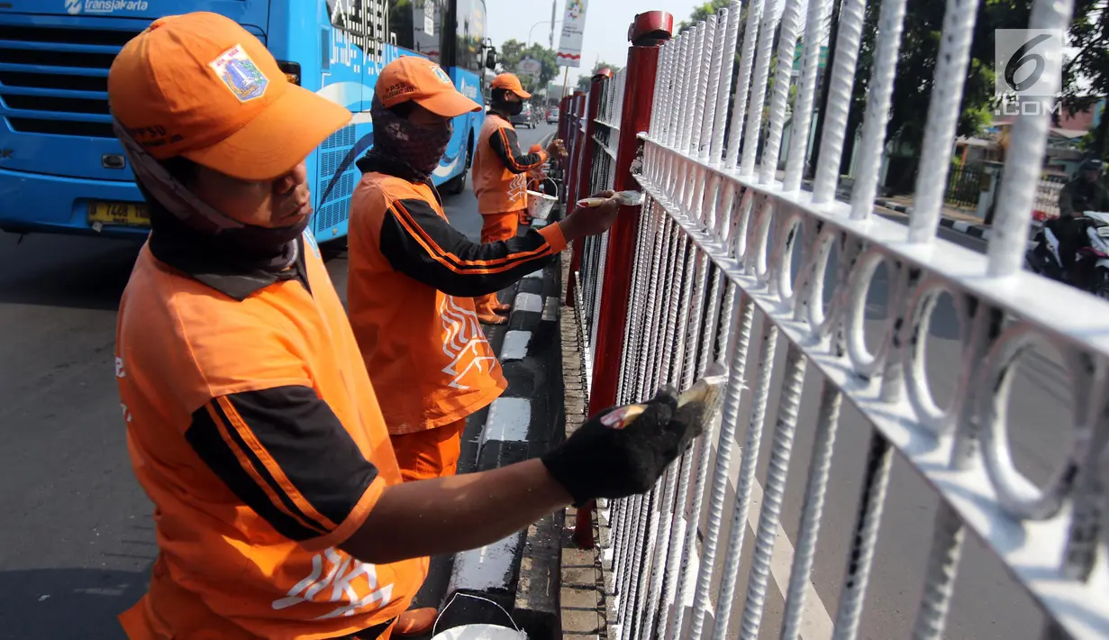 Petugas PPSU Kelurahan Kramat Jati melakukan pengecatan ulang pagar pembatas Jalan Raya Bogor, Jakarta, Selasa (17/7). Upaya penataan sekaligus mempercantik kawasan terus dilakukan jelang Asian Games dan Hari Kemerdekaan RI. (Liputan6.com/Arya Manggala)