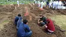 Sebuah keluarga berdoa di salah satu makam khusus Covid-19 di TPU Tegal Alur, Jakarta, Kamis (17/12/2020). Hingga hari ini, intensitas pemakamanan korban covid-19 di DKI masih tinggi dengan rata-rata yang dimakamkan mencapai 30 hingga 38 jenazah per hari. (merdeka.com/Arie basuki)