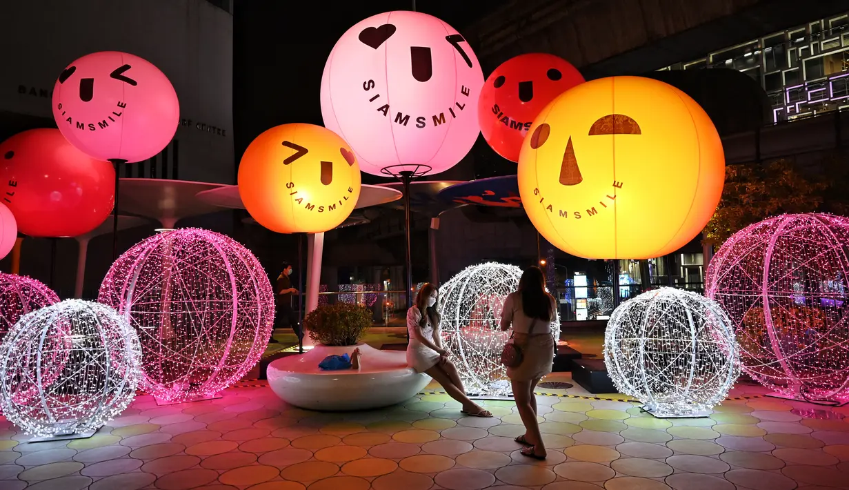 Orang-orang berfoto dengan dekorasi Natal di depan pusat perbelanjaan di Bangkok (21/12/2021). Menyambut Natal, dekorasi unik dan lucu ditampilkan di depan pusat perbelanjaan di Bangkok. (AFP/Lillian Suwanrumpha)