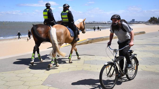 Polisi berpatroli dengan menunggang kuda di sepanjang St Kilda Esplanade di Melbourne (26/10/2020). Pejabat kesehatan Australia melaporkan tidak ada kasus virus corona baru atau kematian di negara bagian Victoria. (AFP Photo/William West)
