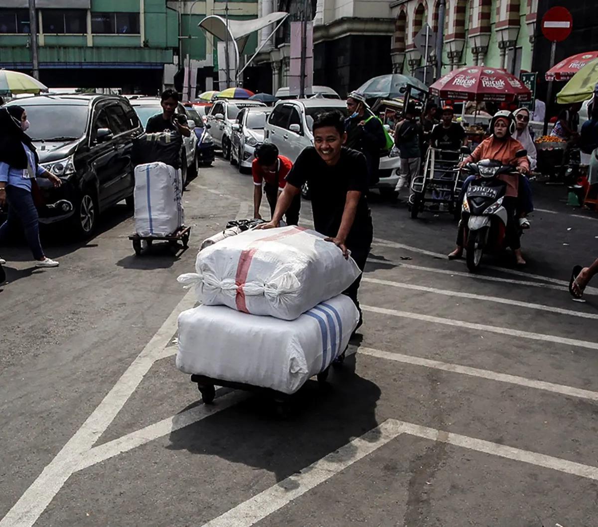 Bermodal troli, mereka menarik maupun mendorong barang-barang yang diantar
