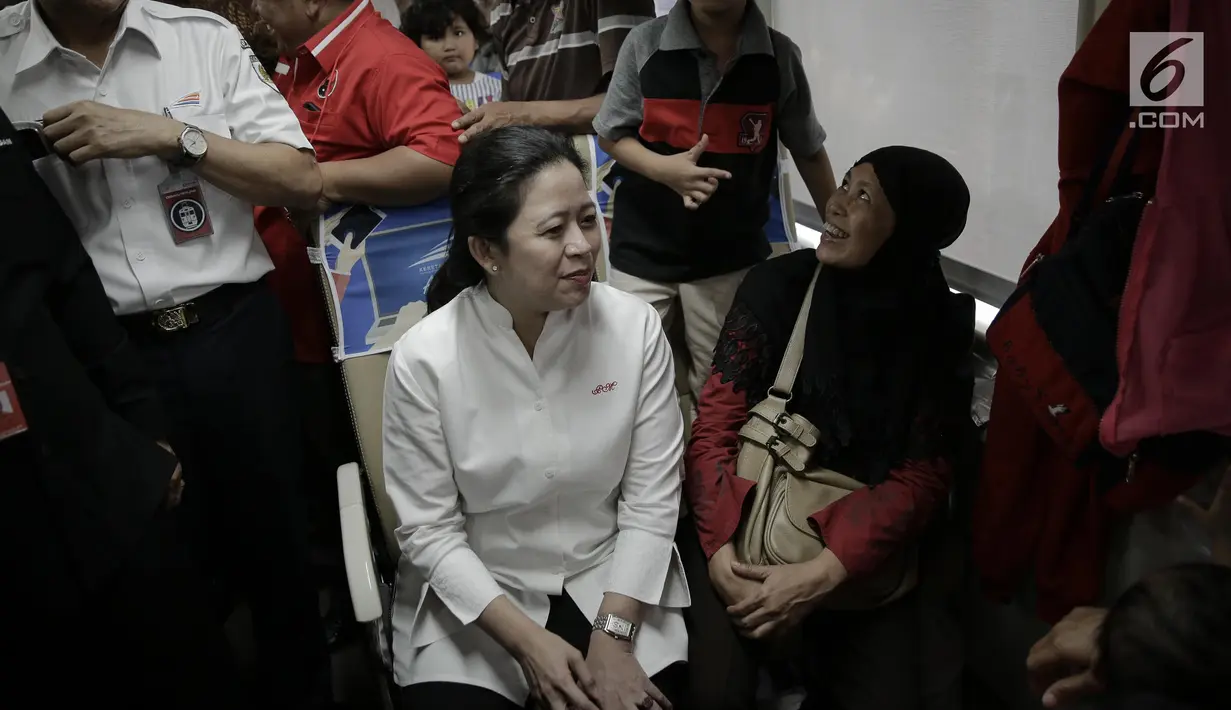 Menko PMK, Puan Maharani berbincang dengan salah satu pemudik di dalam kereta sebelum keberangkatan di Stasiun Senen, Jakarta, Rabu (21/6). Puan juga menggunakan topi kepala stasiun untuk menandai keberangkatan kereta. (Liputan6.com/Faizal Fanani)