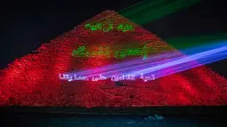 Kementerian barang antik Mesir menerangi Piramida Besar Mesir dengan pesan dukungan bagi tenaga kesehatan yang memerangi pandemi corona Covid-19 di Giza, Senin (30/3/2020). Piramida tersebut menampilkan pesan dalam bahasa Arab dan Inggris dalam cahaya berwana biru dan hijau. (AP/Nariman El-Mofty)