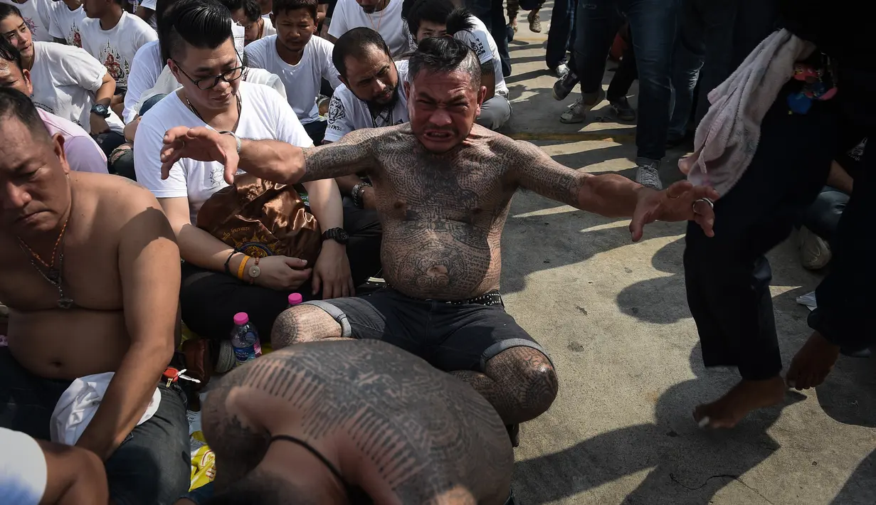 Ekspresi seorang pria yang badanya penuh tato saat kesurupan dalam festival tato suci di Biara Wat Bang Phra, Nakhon Pathom, Thailand (3/3). Dalam festival ini para peserta mengisi ulang kekuatan tato suci. (AFP Photo/Lillian Suwanrumpha)