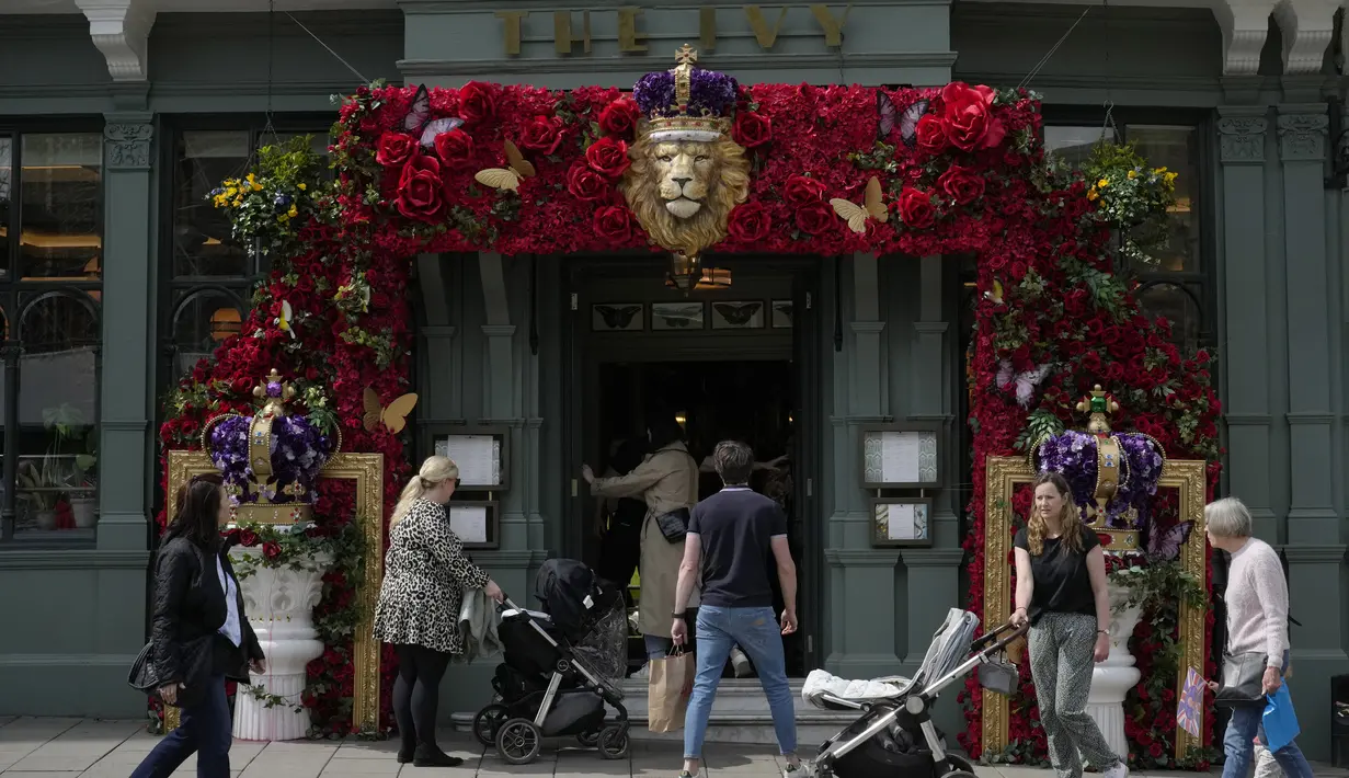 Sebuah restoran yang didekorasi untuk penobatan Raja Charles III dilihat oleh para turis di Windsor, Inggris, Jumat, 5 Mei 2023. Raja Charles III akan dinobatkan sebagai Raja di Westminster Abbey pada Sabtu, 6 Mei. (AP Photo/Andrea Alexandru)