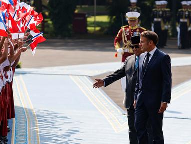 Presiden Republik Indonesia Prabowo Subianto (kedua kanan) bersama Presiden Prancis Emmanuel Macron melihat anak-anak sekolah yang mengibarkan bendera kedua negara dalam rangkaian upacara penyambutan di Istana Merdeka, Jakarta, Rabu 28 Mei 2025. (Ludovic MARIN/AFP)