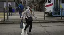 Seorang perempuan lansia yang mengenakan masker berjalan sendirian di jalan di Hong Kong, Minggu (13/3/2022). Pemimpin Hong Kong Carrie Lam mengatakan infeksi Covid-19 di kota itu belum melewati puncaknya meskipun jumlah kasus harian baru-baru ini sedikit menurun. (AP Photo/Kin Cheung)