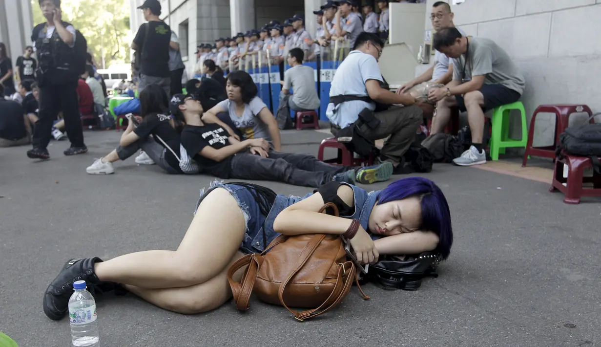 Seorang Wanita tidur di jalanan sekitar Gedung Kementerian Pendidikan, Taipei, Taiwan, Jumat (31/7/2015). Ratusan pelajar Taiwan turun ke jalan menuntut pengunduran diri menteri pendidikan yang mengedarkan buku sekolah menyesatkan. (REUTERS/Pichi Chuang)