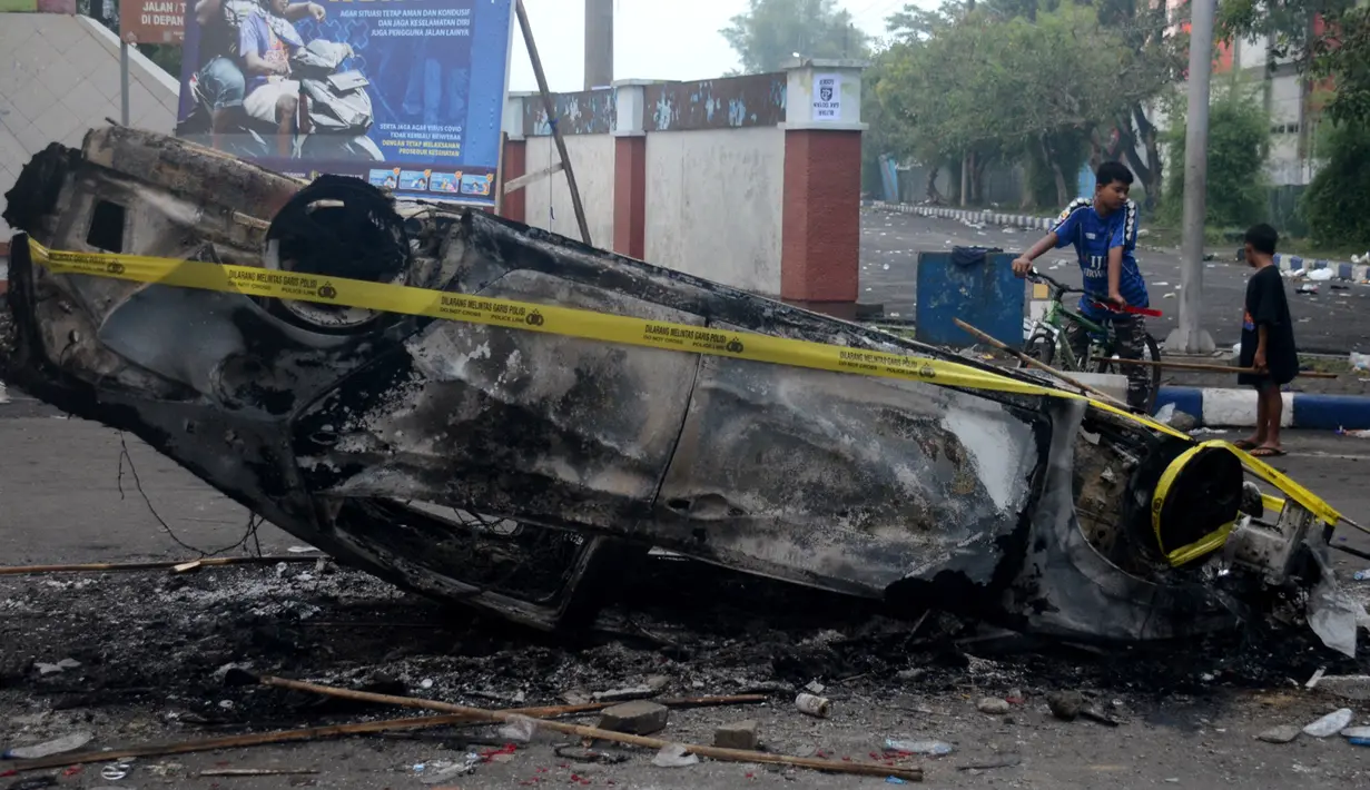 Mobil dibakar di luar Stadion Kanjuruhan, Malang, Jawa Timur, Minggu (2/10/2022). Sebanyak 127 orang tewas ketika para penggemar yang marah menyerbu lapangan sepak bola setelah pertandingan antara Arema FC dan Persebaya Surabaya pada 1 Oktober 2022. (PUTRI/AFP)
