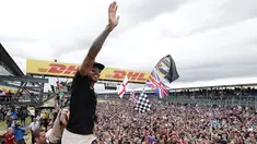 Pembalap Formula 1, Lewis Hamilton merayakan kemenangan bersama pengemarnya usai berlaga di Grand Prix Formula 1 Silverstone di Inggris, (5/7/2015). Hamilton berhasil finish di urutan pertama dengan waktu 1 jam 31 menit 27,729 detik. (Reuters/Hoch Zwei)
