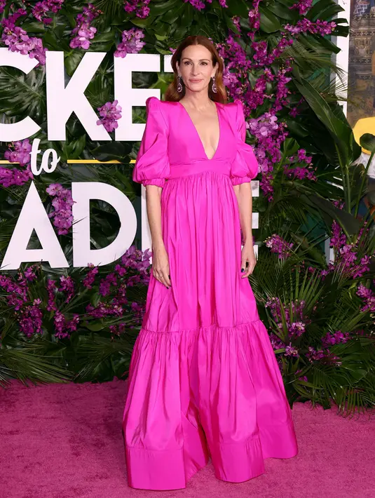 Julia Roberts berpose di karpet merah saat tiba menghadiri pemutaran perdana film "Ticket to Paradise" di Regency Village Theatre di Westwood, California, pada 17 Oktober 2022. Aktris berusia 54 tahun itu tampil memukau dalam balutan gaun hot pink yang melambai ke lantai. (Tommaso Boddi/Getty Images/AFP)