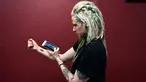 Hanna Washlake mendengarkan tato gelombang suara yang mengeluarkan pesan dari ibunya di Black Raven Tattoo California, 12 April 2018. Soundwave Tattoo menghasilkan suara berdurasi satu menit yang berasal dari pola gelombang audio. (AFP/FREDERIC J. BROWN)