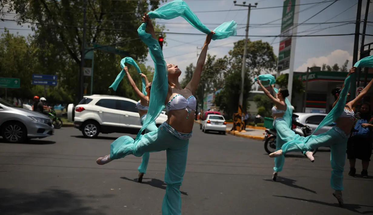 Balerina menampilkan tarian balet saat lampu merah di tengah jalanan Mexico City, 28 Juli 2018. Para balerina dari sanggar Ardentia itu membawakan tarian klasik  untuk menghibur para pengendara di persimpangan yang macet. (AP/Emilio Espejel)