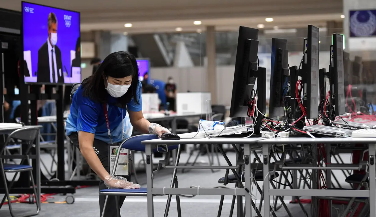 Seorang relawan membersihkan meja dengan tisu alkohol di Main Press Centre di Tokyo pada 20 Juli 2021, menjelang Olimpiade Tokyo 2020. (AFP/Jung Yeon-je)