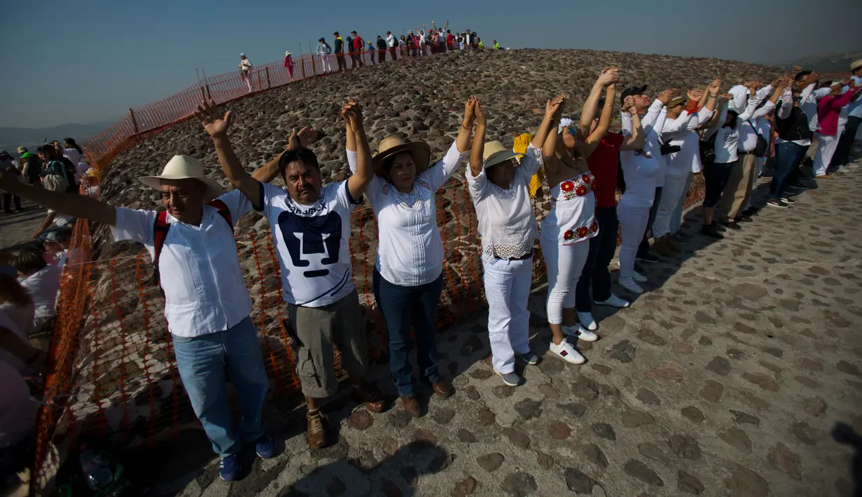 Wisatawan mengangkat tangan merasakan hangatnya sinar mentari pada upacara menyambut fenomena equinox di depan Piramida Matahari, Teotihuacan, Meksiko, Senin (20/3). Equinox terjadi dua kali dalam setahun, yakni Maret dan September. (AP/Rebecca Blackwell)