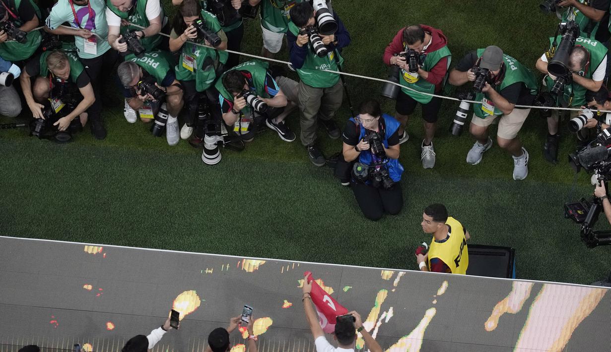 <p>Fotografer memotret Cristiano Ronaldo saat berjalan ke bangku timnya pada awal pertandingan babak 16 besar Piala Dunia antara Portugal dan Swiss, di Stadion Lusail di Lusail, Qatar, Selasa (6/12/2022). Ronaldo mengawali laga dari bangku cadangan. Dia baru masuk menggantikan Joao Felix pada menit 73 ketika Portugal sudah unggul 5-1. (AP Photo/Thanassis Stavrakis)</p>