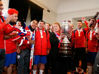 Presiden Chili, Michelle Bachelet dan pemain Chile berpose dengan trofi usai mengalahkan Argentina di final Copa America 2015 di Istana nasional, Chili (4/7/2015). Chili menang lewat adu penalti atas Argentina dengan skor 4-1. (REUTERS/Rodrigo Garrido)