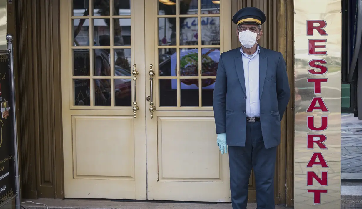 Seorang penjaga mengenakan masker  berdiri di depan sebuah restoran di Teheran, Iran (26/2/2020). Kementerian Kesehatan dan Pendidikan Kedokteran Iran pada (26/2) mengumumkan 139 orang telah terinfeksi coronavirus baru dan 19 di antaranya meninggal dalam sepekan terakhir. (Xinhua/Ahmad Halabisaz)