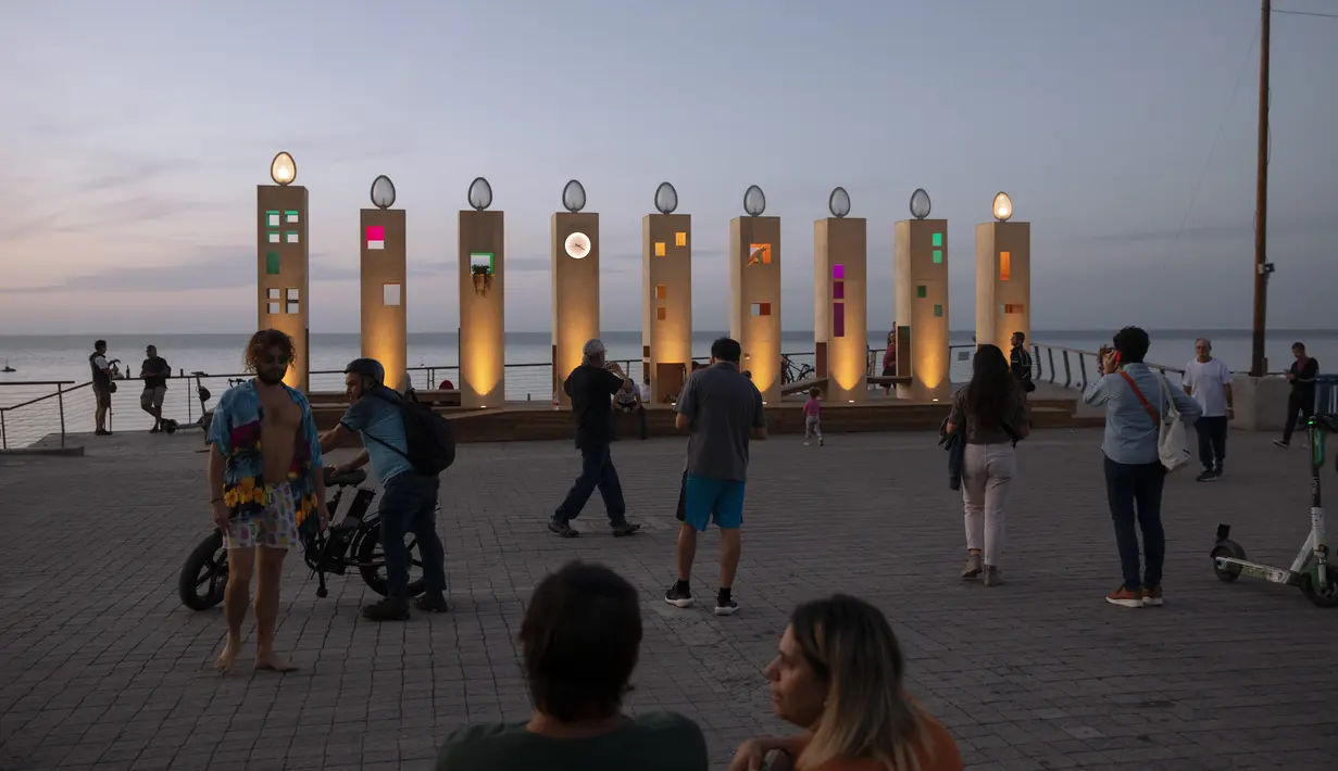 Orang-orang mengunjungi menorah Hanukkah raksasa selama hari libur Yahudi Hanukkah, di Tel Aviv, Minggu (28/11/2021). Hanukkah, juga dikenal sebagai Festival Cahaya, adalah peringatan delapan hari pemberontakan Yahudi pada abad kedua SM. (AP Photo/Oded Balilty)