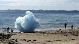 Anak-anak bermain disamping bongkahan es berukuran raksasa di Nuuk, Greenland, 5 Juni 2016. Cuaca ekstrem membuat sebagaian gunung es mencair yang membuat naiknya air laut. (REUTERS / Alister Doyle)