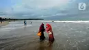 Wisatawan yang mengenakan masker bermain air saat mengunjungi Pantai Anyer di Cilegon, Banten, Minggu (25/10/2020). Akhir pekan dimanfaatkan warga Jakarta dan sekitarnya untuk berwisata dengan tetap menerapkan protokol kesehatan Covid-19. (merdeka.com/Arie Basuki)