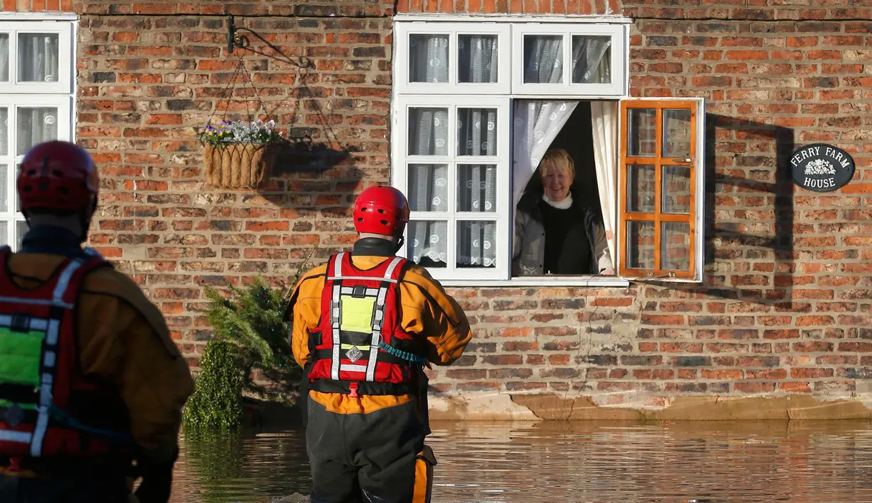 Petugas saat ingin mengevakuasi warga yang terjebak banjir dirumahnya di wilayah York, Inggris utara, Minggu (27/12). Pada Sabtu (5/12) lalu Badai Desmond telah menerjang Inggris yang mengakibatkan ribuan rumah terendam air. (REUTERS/Phil Noble)