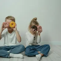 Ilustrasi dua anak yang sedang memegang makanan manis (Sumber: Pexels.com/Tima Miroshnichenko)