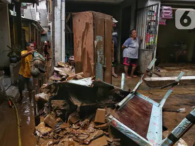 Warga membersihkan sisa lumpur yang tertinggal di permukiman mereka yang ada di sekitar jalan layang Kalibata-Cililitan, Jakarta, Rabu (5/3/2025). (Liputan6.com/Angga Yuniar)