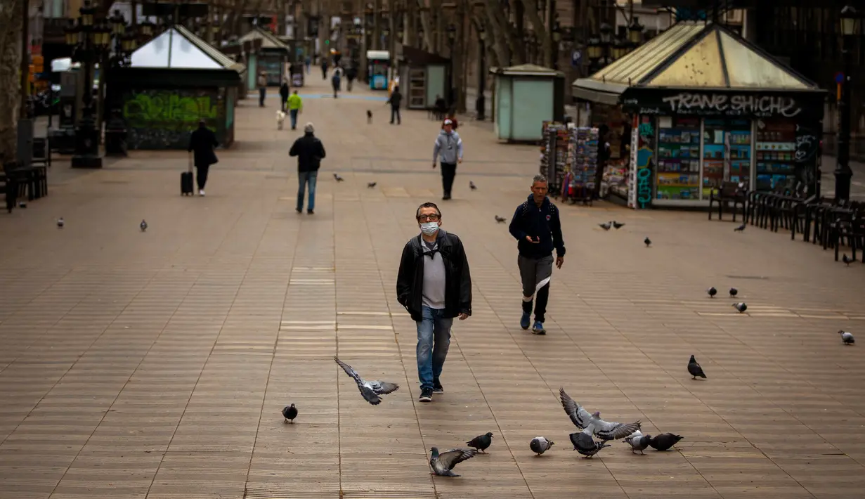 Warga berjalan di sepanjang La Ramblas, Barcelona, Spanyol, Minggu (15/3/2020). Pemerintah Spanyol memberlakukan lockdown setelah negara berpenduduk 47 juta jiwa itu terdampak virus corona COVID-19 paling parah kedua di Eropa setelah Italia. (AP Photo/Emilio Morenatti)