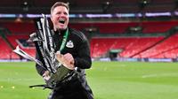 Pelatih kepala Newcastle United asal Inggris, Eddie Howe, merayakan kemenangan dengan trofi Piala Liga setelah memenangkan pertandingan final Piala Liga Inggris antara Liverpool dan Newcastle United di Stadion Wembley, London barat laut pada 16 Maret 2025. Newcastle United menang dalam Piala Liga Inggris 2-1 melawan Liverpool. (Glyn KIRK/AFP)