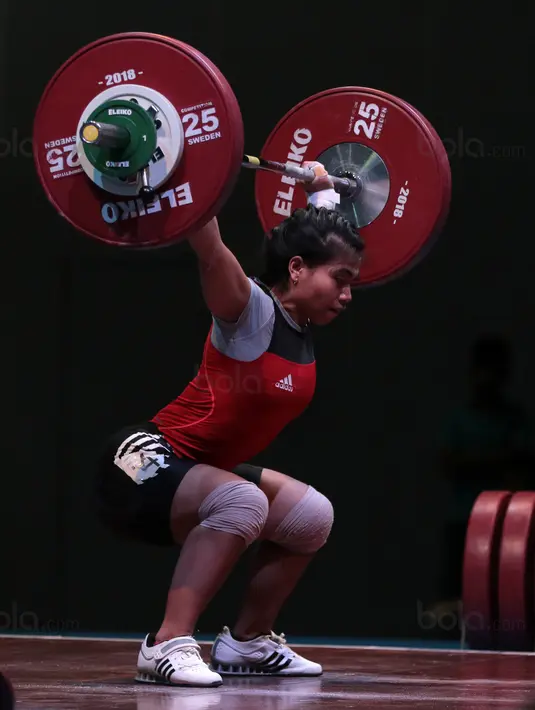Sri Wahyuni berkonsentrasi mengangkat beban saat turun pada kelas 48 kg di Hall A Arena PRJ, Jakarta, Rabu (11/2/2018). Sri Wahyuni meraih medali emas dengan total angkatan 187 kg. (Bola.com/Nicklas Hanoatubun)