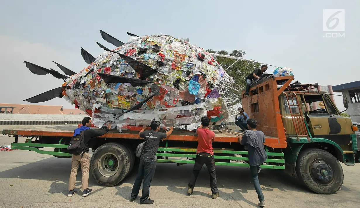 Aktivis pemerhati lingkungan menurunkan monster plastik dari atas truk saat aksi Tolak Penggunaan Plastik Sekali Pakai di Pelabuhan Sunda Kelapa, Jakarta, Sabtu (20/7/2019). Monster plastik itu berupa rangka berbentuk ikan anglerfish yang ukurannya sebesar mobil sampah (Liputan6.com/Herman Zakharia)