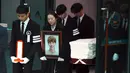 Minho (kiri) membawa plakat pada prosesi pelepasan jenazah Jonghyun SHINee menuju tempat pemakaman dari Asan Hospital, Seoul, Kamis (21/12). Minho berusaha tegar saat memimpin iringan bersama kakak Jonghyun yang membawa foto sang adik. (JUNG Yeon-Je/AFP)