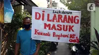 Warga berjalan di salah satu gang yang ditutup secara mandiri di kawasan Tambora, Jakarta, Sabtu (4/4/2020). Penutupan akses masuk kawasan ini untuk membatasi kegiatan warga dan mencegah penyebaran serta penularan virus COVID-19. (Liputan6.com/Helmi Fithriansyah)