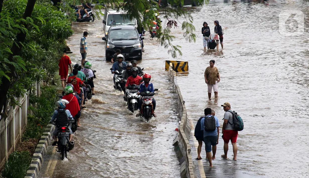 Pengendara dan pejalan kaki melewati perempatan Green Garden, Kedoya, Jakarta, Jumat (3/1/2020). Hingga hari ke-3, banjir masih menggenangi sekitar kawasan perempatan Green Garden, Kedoya akibatnya pengendara harus lebih waspada menghindari mesin kemasukan air. (Liputan6.com/Helmi Fithriansyah)
