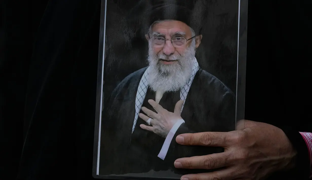 Seorang wanita memegang poster mendiang Pemimpin Tertinggi Iran Ayatollah Ali Khamenei selama prosesi pemakamannya di Teheran, Iran, Senin, 6 Juli 2026. (AP Photo/Vahid Salemi)