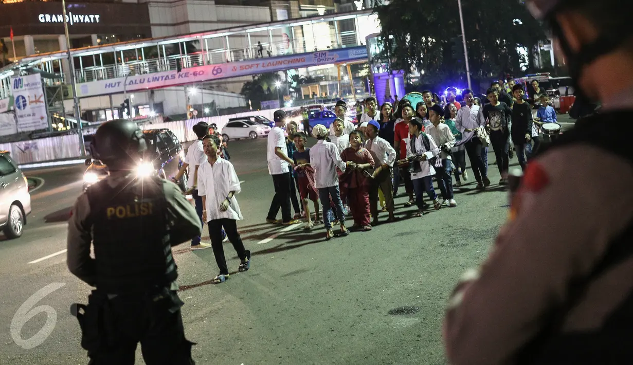 Warga yang sedang takbiran melintas didepan petugas Brimob yang berjaga-jaga dikawasan Bunderan HI, Jakarta, (6/7). Perketat pengamana tersebut dilakukan untuk mengantisipasi pasca bom bunuh diri di halaman Mapolres Solo.(Liputan6.com/Faizal Fanani)