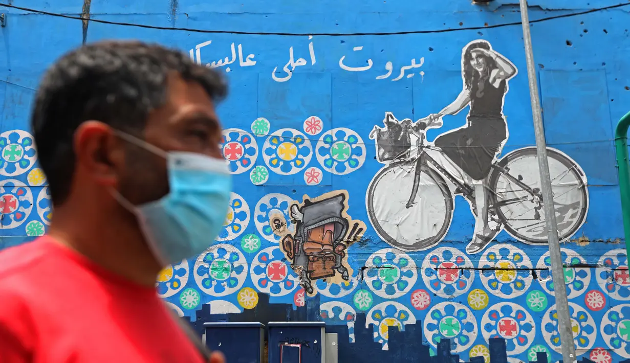 Seorang pria berjalan melewati sebuah grafiti yang mendorong kegiatan bersepeda di Beirut, Lebanon (11/6/2020). Belakangan ini, kegiatan bersepeda menjadi aktivitas yang lazim di Lebanon sejak pemerintah memberlakukan pembatasan guna meredam pandemi COVID-19. (Xinhua/Bilal Jawich)