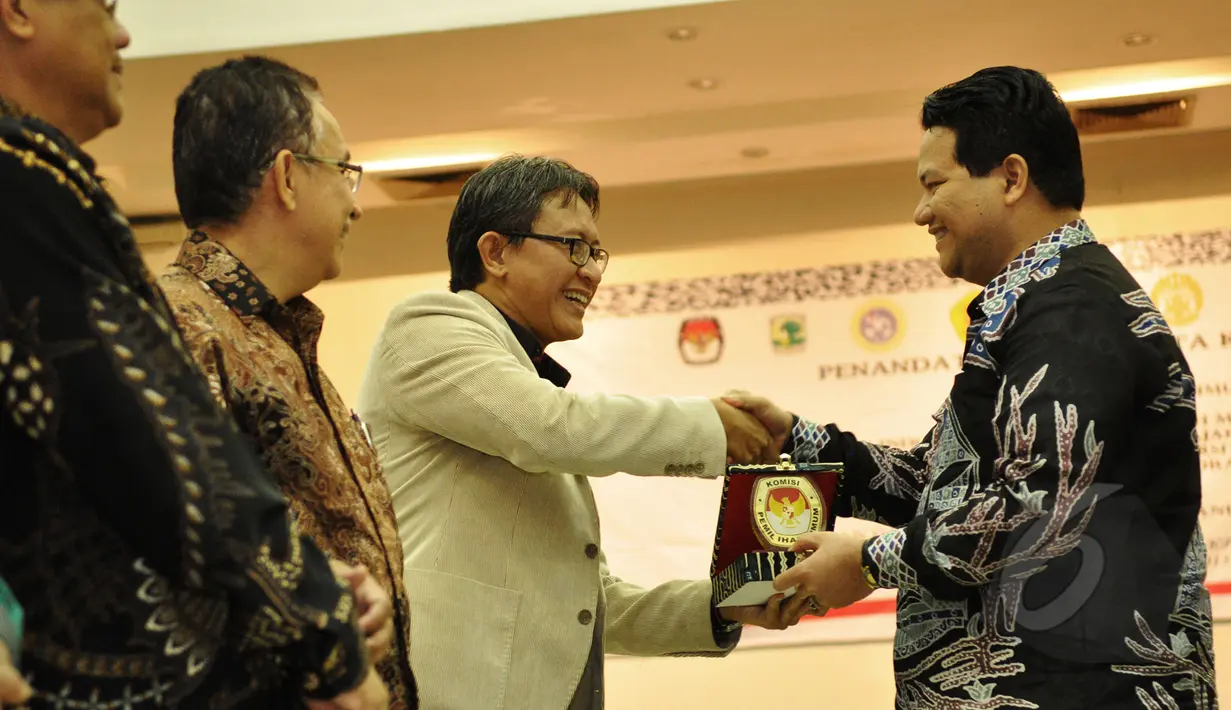 Ketua Komisi Pemilihan Umum (KPU) RI Husni Kamil Manik (kanan) menyerahkan cinderamata usai penandatanganan MoU antara KPU RI dengan sembilan perguruan tinggi di Gedung KPU, Jakarta, Kamis (12/3/2015). (Liputan6.com/Faizal Fanani)