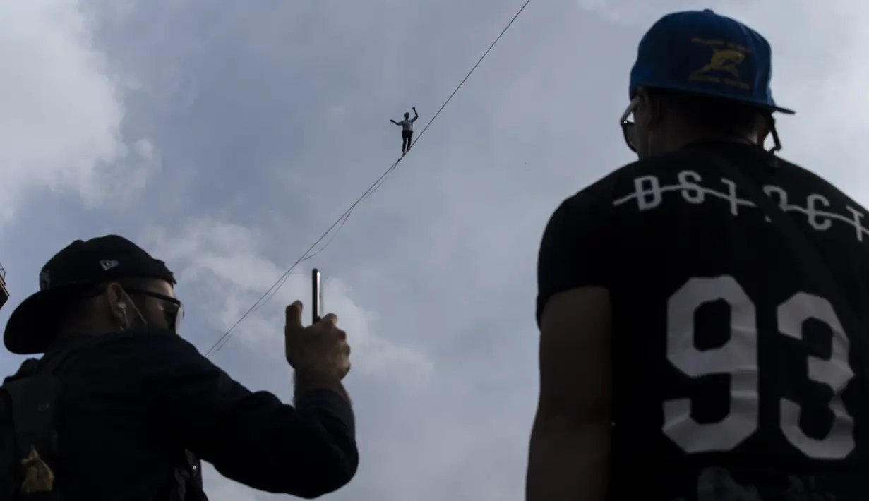 Akrobatik Prancis Nathan Paulin mencoba berjalan meniti seutas tali slackline dari Menara Eiffel melintasi Sungai Seine, di Paris, Minggu (19/9/2021). Nathan Paulin mendapat tepuk tangan yang meriah dari penonton. (AP Photo/Lewis Joly)