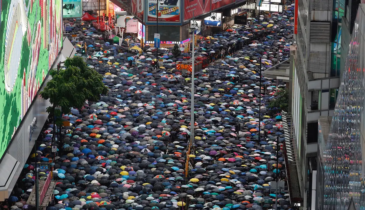 Pengunjuk rasa membawa payung saat menuju Victoria Park, Hong Kong, Minggu (18/8/2019). Puluhan ribu massa pro-demokrasi membawa payung saat hujan mengguyur Victoria Park dan sekitarnya. (AP Photo/Vincent Yu)