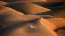 Sejumlah pemuda berlari melintasi gundukan pasir di Gurun Liwa, Abu Dhabi, Uni Emirat Arab, Sabtu (9/1/2021). Elang telah terhubung dengan budaya Uni Emirat Arab selama berabad-abad. (Karim SAHIB/AFP)