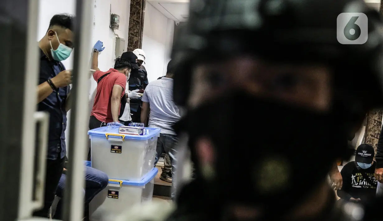 Petugas kepolisian membawa boks berisi barang bukti hasil temuan dari penggeledahan eks Kantor DPP FPI, Petamburan, Jakarta, Selasa (27/4/2021). Penggeledahan tersebut usai Munarman ditangkap sore tadi di kediamannya. (Liputan6.com/Faizal Fanani)