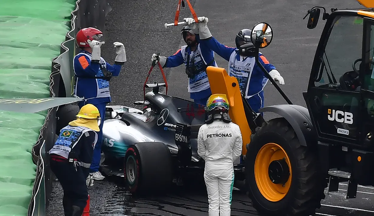 Pembalap Mercedes, Lewis Hamilton keluar dari mobilnya usai menabrak saat kualifikasi F1 GP Brasil di sirkuit Interlagos di Sao Paulo, Brasil (11/11). Hamilton juga tidak dapat menyelesaikan kualifikasi GP Brasil. (AFP Photo/Nelson Almeida)